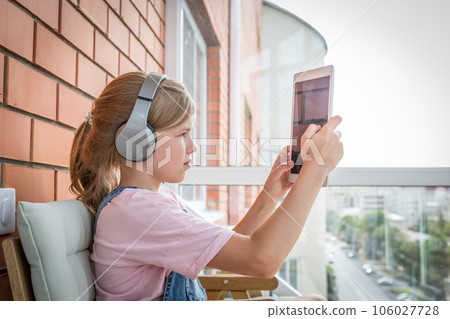 A young girl enjoying listening to music on her headphone with tablet 106027728