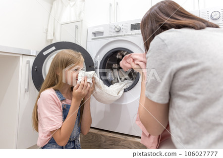 Happy family mother housewife and child daughter in laundry with washing machine and clothes 106027777