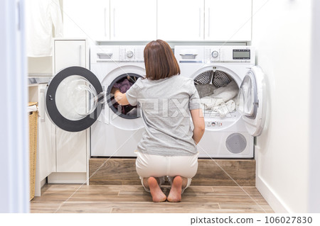Woman putting clothes to washing machine for wash Woman putting clothes to washing machine for wash 106027830