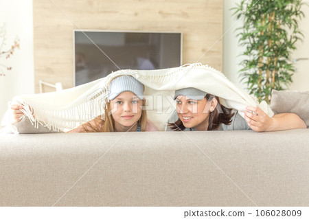Mother and daughter happ family concept. wearing sleeping mask and having fun on sofa in living room Mother and daughter happ family concept. wearing sleeping mask and having fun on sofa in living room 106028009