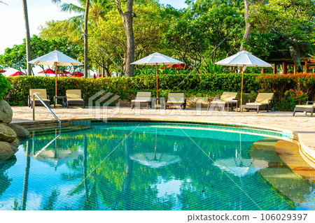 Beautiful luxury umbrella and chair around outdoor swimming pool in hotel and resort with coconut palm tree on sunset  or sunrise sky 106029397
