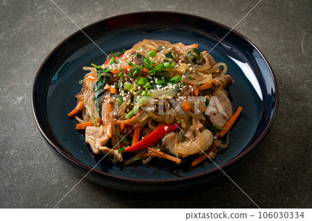 japchae or stir-fried Korean vermicelli noodles with vegetables and pork topped with white sesame 106030334