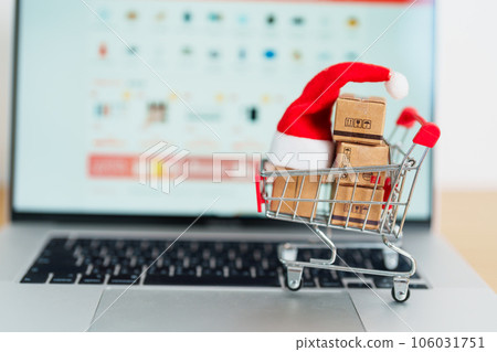 Christmas Online Shopping concept. Boxes with shopping cart on a laptop computer. Sale and discount during Christmas and New Year holiday, ecommerce, shipping delivery, logistics and Cyber Monday 106031751