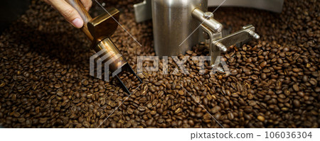 Professional coffee roaster working with modern automated roasting machine in the coffee roasting factory. Food and beverage business concept. Professional coffee roaster working with modern automated roasting machine in the coffee roasting factory. Food and beverage business concept. 106036304