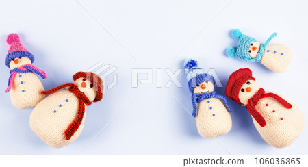 Knitted snowmen in colorful hats and scarves on a blue background. Concept of Christmas, New Year and winter fairy tale. Creative knitting of toys for children, home decoration. 106036865