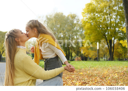 young blonde mother kneeling and kissing the preschooler daughter in the park on a sunny day young blonde mother kneeling and kissing the preschooler daughter in the park on a sunny day 106038406