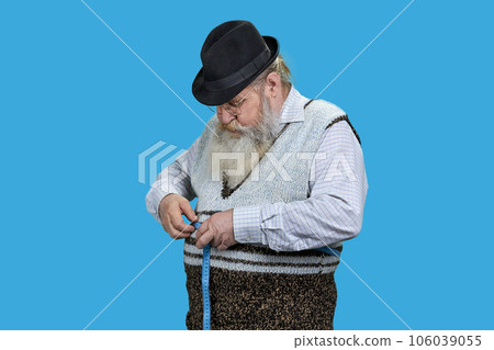 Senior man measuring waist with a blue tape. Lose weight concept. Isolated on vivid blue background. 106039055