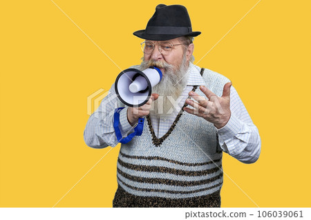 Portrait of expressive aged man giving a speech in megaphone. Isolated on vivid yellow background. 106039061