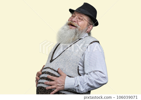 Old bearded man laughing and touching his stomach. Isolated on pastel yellow. Old bearded man laughing and touching his stomach. Isolated on pastel yellow. 106039071