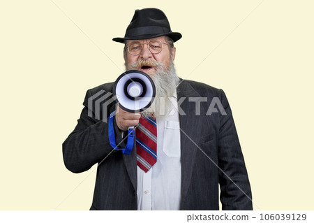 Portrait of aged senior man giving a speech in megaphone. Pastel yellow background. Portrait of aged senior man giving a speech in megaphone. Pastel yellow background. 106039129