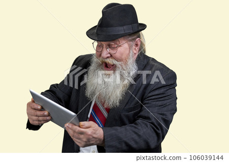 Portrait of excited senior man with tablet pc. Isolated on yellow. Portrait of excited senior man with tablet pc. Isolated on yellow. 106039144