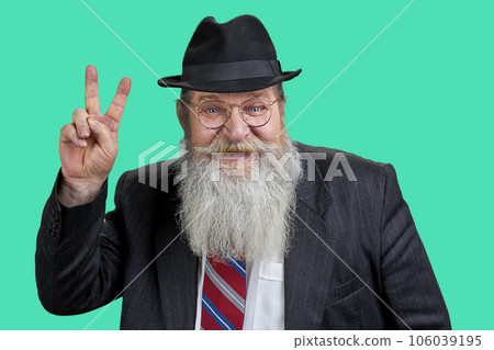 Portrait of happy bearded man showing victory sign. Isolated on green. 106039195