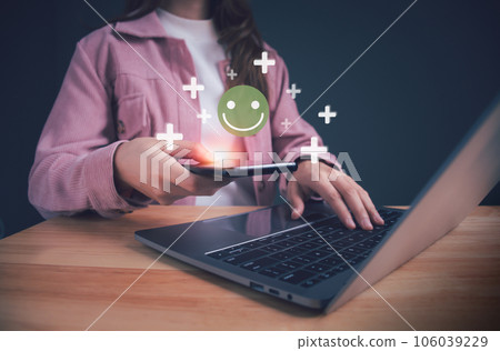 Businesswoman holding smartphone showing green happy smile face. Concept of satisfaction survey, good feedback rating, positive customer review, experience, child wellness and world mental health day. 106039229