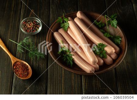 Raw pork sausages on a vintage plate with parsley and spices. Fast food or street food concept Raw pork sausages on a vintage plate with parsley and spices. Fast food or street food concept 106039504