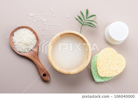 Homemade cosmetic rice water with beauty kit on beige background, top view copy space, home spa flat lay 106040000