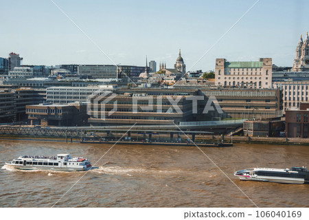 Aerial view of Cruise moving on river Thames. Buildings with blue sky in background. Downtown district in London on sunny day. 106040169