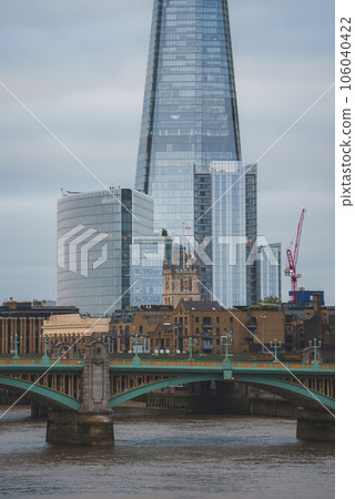 Southwark bridge and cathedral with apartments and modern buildings in background. The Shard at banks of Thames river in city with sky in background. Famous tourist attraction in London. 106040422