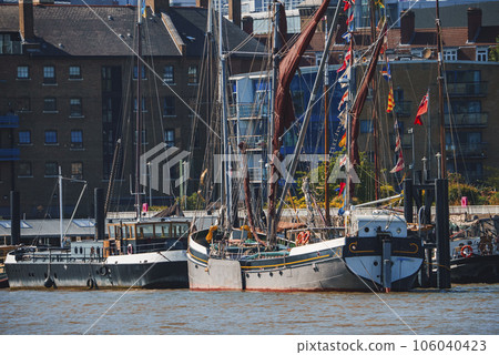 Boats moored at Thames riverbank. Residential apartments in background. Buildings in district of London during sunny day. 106040423