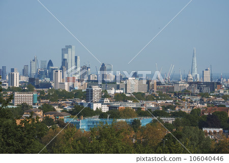 Scenic view of London cityscape with blue sky in background. Modern skyscrapers amidst residential buildings. High angle view of urban development in London. Scenic view of London cityscape with blue sky in background. Modern skyscrapers amidst residential buildings. High angle view of urban development in London. 106040446