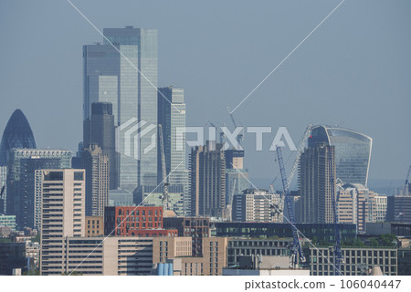 View of famous financial skyscrapers amidst residential district. Modern city with blue sky in background. High angle view of urban development in London. View of famous financial skyscrapers amidst residential district. Modern city with blue sky in background. High angle view of urban development in London. 106040447