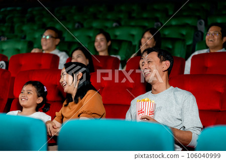 Asian family with father, mother and daughter enjoy and happy to watch movie together in theater 106040999