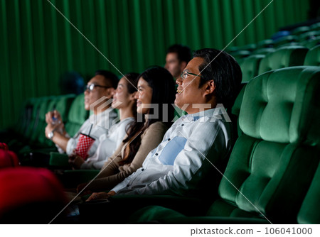 Asian man look enjoy and happy during watch movie in cinema theater and sit near other young woman 106041000