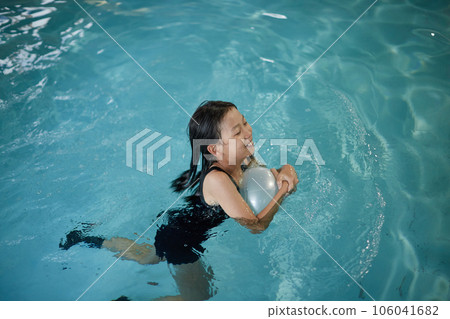 A child girl practicing swimming in an indoor pool A child girl practicing swimming in an indoor pool 106041682
