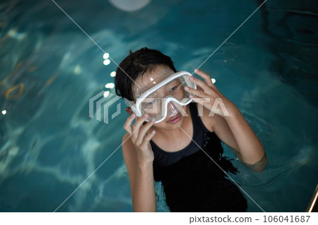 A child girl practicing swimming in an indoor pool 106041687
