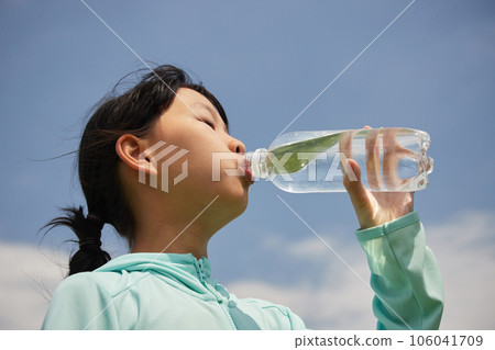A child drinking water from a pet bottle under the scorching sun in midsummer A child drinking water from a pet bottle under the scorching sun in midsummer 106041709