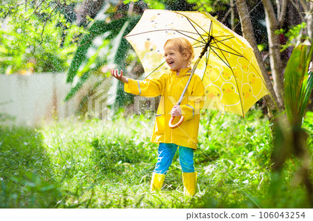 Child playing in the rain. Kid with umbrella. Child playing in the rain. Kid with umbrella. 106043254