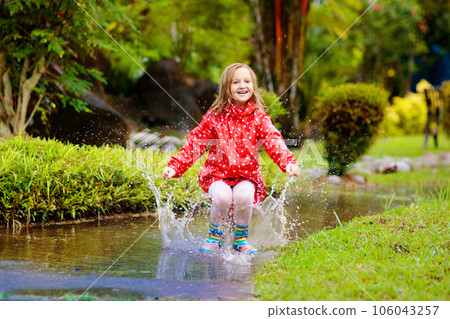 Child playing in puddle. Kids jump in autumn rain 106043257