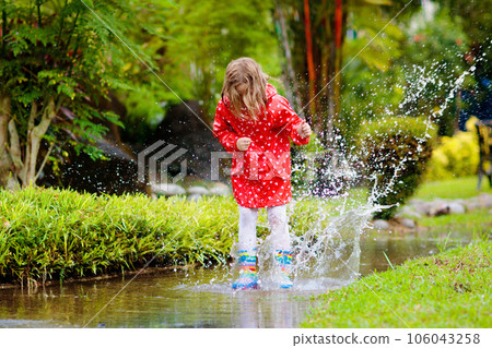Child playing in puddle. Kids jump in autumn rain 106043258