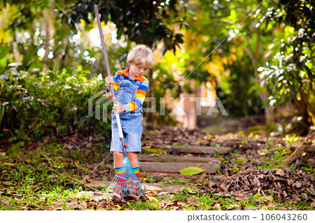 Child and rake in autumn garden. Kid raking leaves Child and rake in autumn garden. Kid raking leaves 106043260