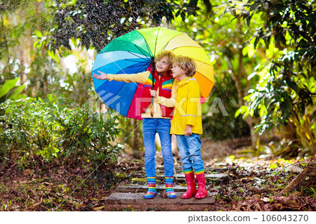 Child playing in autumn rain. Kid with umbrella. 106043270