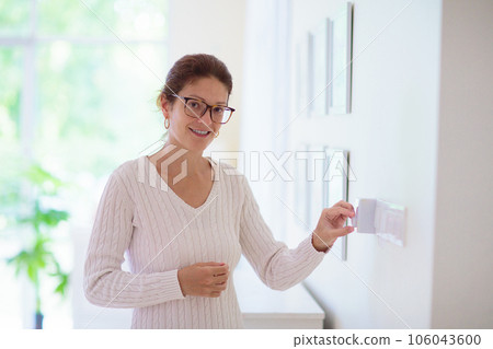 Woman adjusting thermostat. Central heating. 106043600