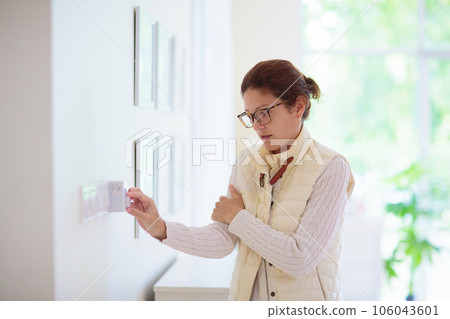 Woman adjusting thermostat. Central heating. Woman adjusting thermostat. Central heating. 106043601
