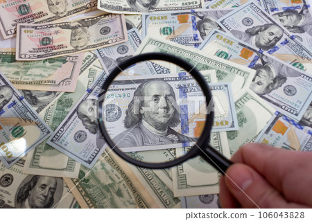 Magnifying glass on the background of bundle dollars - texture, background 106043828
