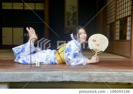 A woman in a beautiful yukata standing on the porch of an old folk house 106044186