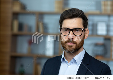 Close up of mature experienced lawyer, serious man in glasses and business suit inside classic office, businessman looking at camera thinking. Close up of mature experienced lawyer, serious man in glasses and business suit inside classic office, businessman looking at camera thinking. 106046059