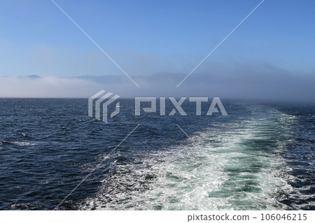 Ship's wake with Port Angeles, Olympic Mountains and fog bank in background. Ship's wake with Port Angeles, Olympic Mountains and fog bank in background. 106046215