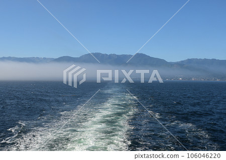 Ship's wake with Port Angeles, Olympic Mountains and fog bank in background. Ship's wake with Port Angeles, Olympic Mountains and fog bank in background. 106046220