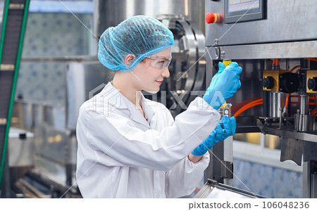 Bottling factory worker inspecting quality of water bottles before shipment. Reverse osmosis system used in plant. water purity and maintaining quality control in bottling process. High quality photo 106048236