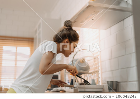 Woman in white t-shirt cooking in the kitchen making lunch. 106048242