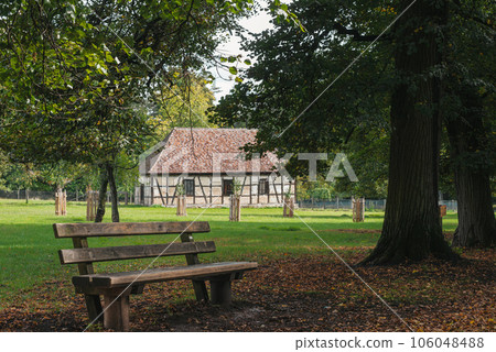 Calm Fall Season in German Park. Beautiful Landscape With Road In Autumn Forest. Bench in the Autumn Park. Maples And Birch Trees With Green, Yellow And Orange Leaves And Footpath In The Woodland In 106048488