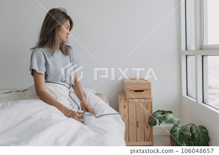 Woman hold a cup of coffee in white bedroom morning with empty space. 106048657