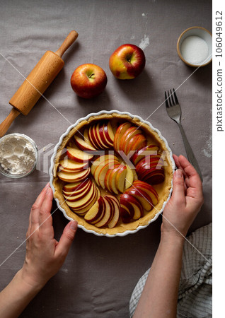 Cooking apple pie pastry. Raw pie with red apples in baking tin 106049612