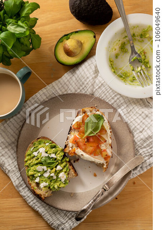 Avocado and salmon toasts with sourdough bread, sliced avocado, cream cheese and basil 106049640