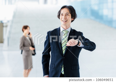 Business person standing in lobby and looking at watch Business person standing in lobby and looking at watch 106049651