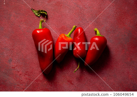 Red chili pepper on red background, top view. Dark and moody photo Red chili pepper on red background, top view. Dark and moody photo 106049654