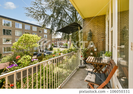 a balcony with two chairs and an umbrella in the sun on a sunny day, taken from inside to outside a balcony with two chairs and an umbrella in the sun on a sunny day, taken from inside to outside 106050331